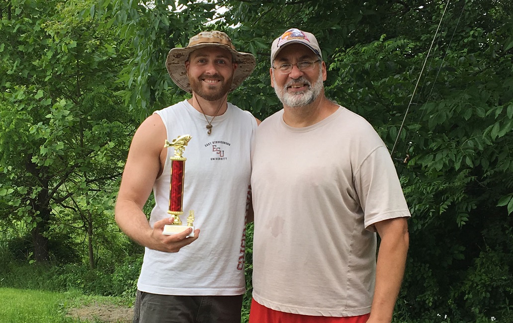 2 men, one holding a trophy